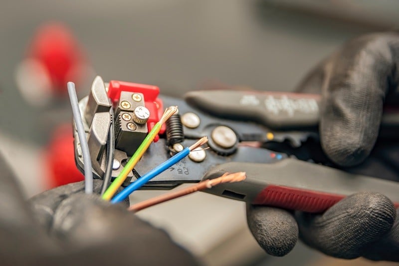 Wire strippers. The electrician cleans the protective insulation from the wire using a wire stripper. The process of connecting wires. close-up